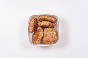 Homemade meat cutlets in a food container on a white table