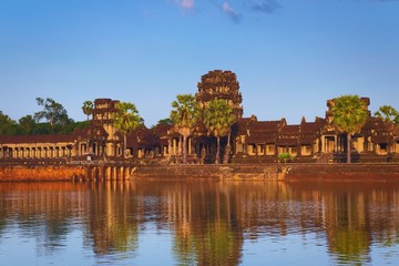 Fototapeta premium Angkor Wat, in Cambodia. Front general view of western outer gate at sunset. Angkor Wat is the largest religious monument in the world, and has been declared UNESCO World Heritage Site