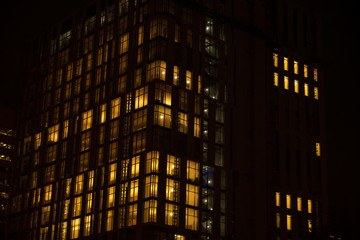 Fototapeta na wymiar Night skyscraper closeup, glowing window. Night work