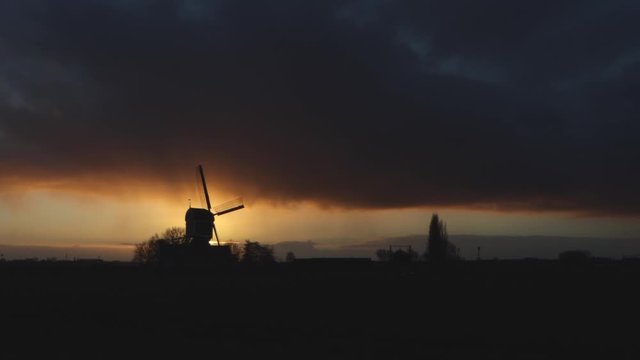 Silhouette of an old windmill in the Netherlands at sunset on a stormy day