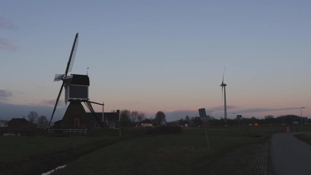 Traditional windmill and modern windmill standing beside each other in the Netherlands
