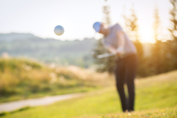 A golf ball floating in the air and Blurry golfer in the background.