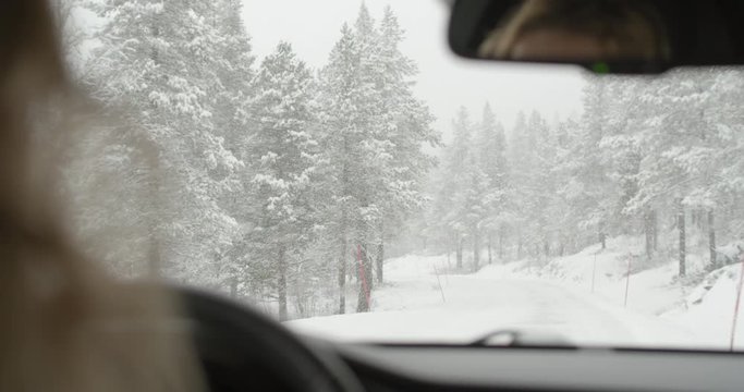 Slow motion handheld wide 4K interior shot of windscreen on car driven by blonde Norwegian woman in blizzard snow storm, in the mountains of Norway. Shot on professional cinema camera.