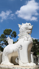 Obraz premium Closeup of white sculpture of ancient lion in front of the temple. Vertical view.