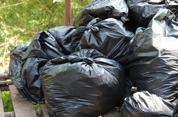 Closeup of a pile of black garbage bags under sunlight.