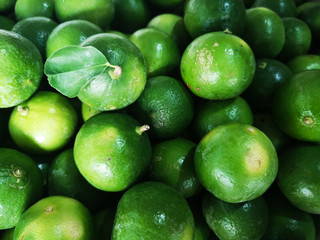 Group of tropical fresh green limes texture background in thai market.