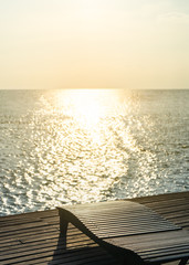 Naklejka na ściany i meble Beautiful sunset with wooden lounge chair and sea