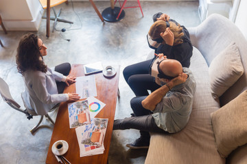 Mature people wearing VR glasses. Smiling couple sitting on sofa with virtual reality headsets and watching examples for home renovation. Technology concept