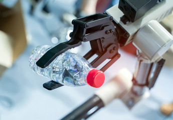robot hand holding a bottle of wate on blurred background, artificial intelligence concept. Automatic industrial machinery equipment.