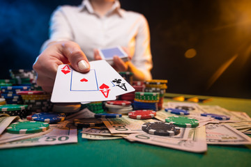 Obraz premium Playing in a casino, online casino. A player opens cards with two aces. Money, poker table, chips. Background for the gaming business, and online casinos.