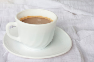 A cup of hot coffee on white tablecloth for the new morning.