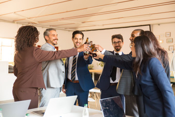 Smiling office managers cheering with beer bottles. Cheerful young people relaxing after hard work. Relaxation, celebration concept