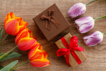 Gift boxes with tulips on wooden boards.