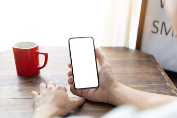 Mockup image blank white screen cell phone.man hand holding texting using mobile on desk at coffee shop.background empty space for advertise text.people contact marketing business,technology