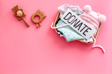 Charity concept. Donate text on box with clothes on pink background top-down copy space