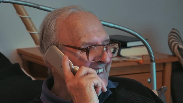 Alter Mann mit Hornbrille telefoniert mit Klapphandy