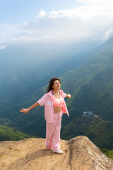 Naklejka premium Girl enjoys a mountain view while standing on a cliff