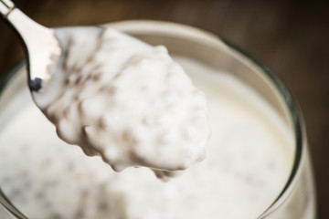 Plain yogurt with chia seeds in glass on the rustic wooden background. Selective focus.