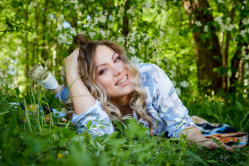 Girl lying on the grass in the park with flowering Apple trees in a spring time