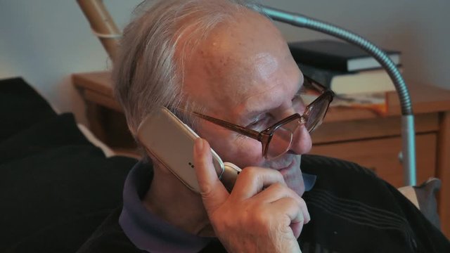 Alter Mann mit Hornbrille telefoniert mit Klapphandy