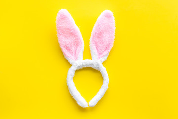 Easter bunny concept. Toy rabbit's ears for head on yellow background top-down copy space