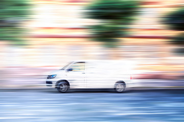 Fototapeta na wymiar White van speeding down a city street.