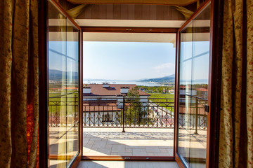 The open door on to the verandah of a luxury cabin with a view of the mountains and the sea.
