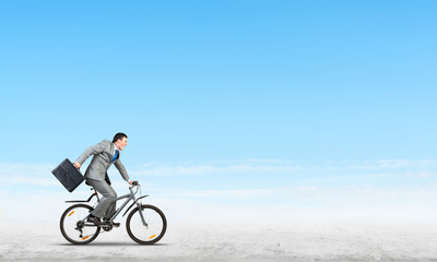 Man wearing business suit riding bicycle outdoor.