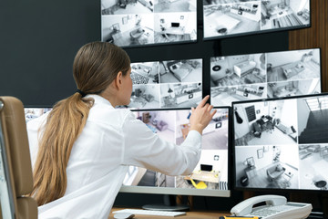 Security guard monitoring modern CCTV cameras indoors