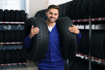 Male mechanic with car tires in auto store © New Africa