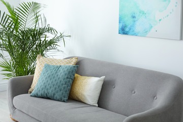 Different soft pillows on sofa in living room
