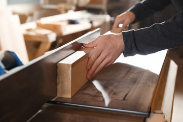 Professional carpenter working with surface planer in workshop, closeup