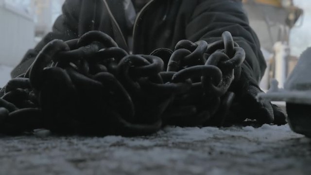 Slow-Motion Shot of Man slamming chains down in the back of a snowy truck
