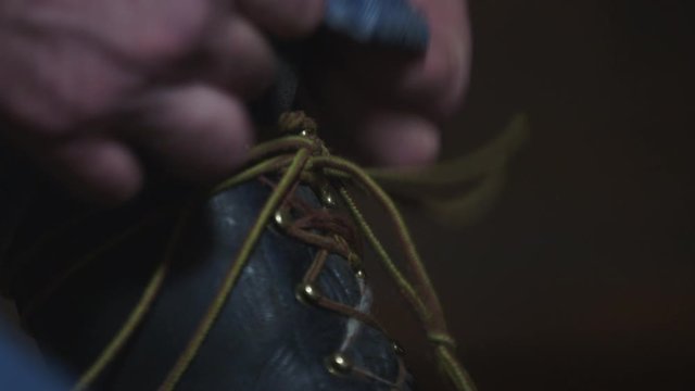 Close-Up Of man putting on work-boots and tying the laces