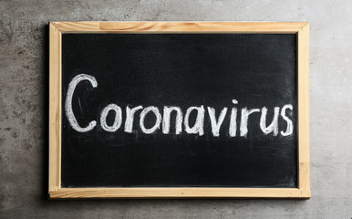 Fototapeta premium Blackboard with word CORONAVIRUS on light grey stone table, top view