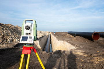 Surveyor GPS system equipment at pipeline construction. Civil engineers surveyors measuring coordinates to precisely lay down pipe tubes for gas distribution in the ground. - obrazy, fototapety, plakaty