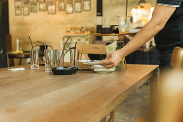 Waiter hand pick up dirty dishes on dinner restaurant.