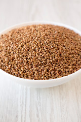 Uncooked Roasted Buckwheat in a white bowl, side view. Close-up.