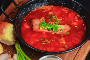 Traditional Ukrainian Russian vegetable borscht. Ukrainian beetroot soup in a bowl with meet, greenery and garlic bread