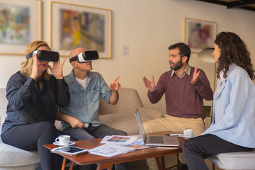 Fototapeta na wymiar Excited mature people testing VR headsets. Concentrated couple sitting on sofa and watching examples of interior design with virtual reality glasses. Technology, innovation concept
