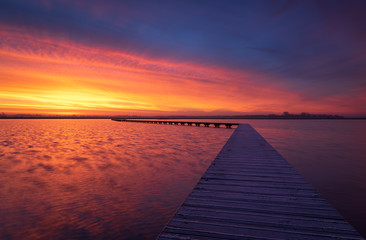 Fototapeta na wymiar Very colorful and tranquil dawn at a jetty in a lake. Groningen, Holland.