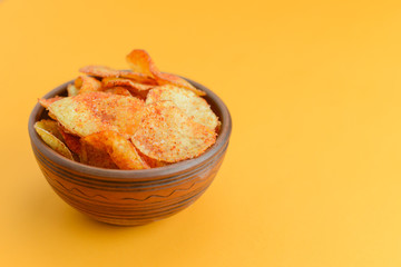 Potato chips, crisp unhealthy chips, junk food, fast food concept. Potato chips in a bowl over bright yellow background.