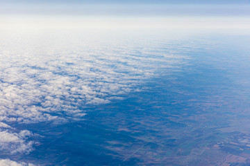 Fototapeta premium Aerial view of fluffy clouds through an airplane window