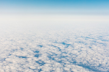 Aerial view of fluffy clouds through an airplane window