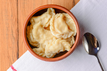 Traditional Ukrainian meat dumplings. Russian boiled pelmeni served in a bowl with sauce on white tablecloth