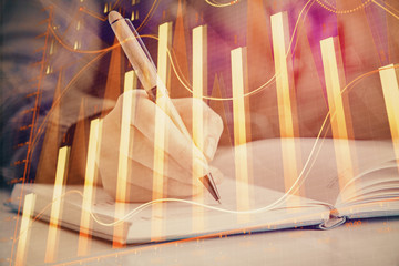 Multi exposure of woman's hands making notes with forex graph hologram. Concept of technical analysis.