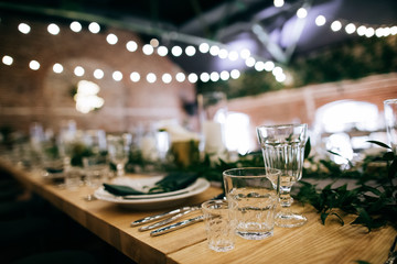 Table set. Festive table decoration in a restaurant with green leaves and candles