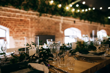 Beautiful table decoration in a restaurant with green leaves and candles
