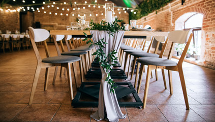  Beautiful wedding table decoration with green branches with leaves and gray fabric in restaurant