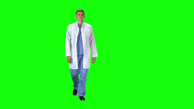 Medical man in white coat going and looking forward against a green background.